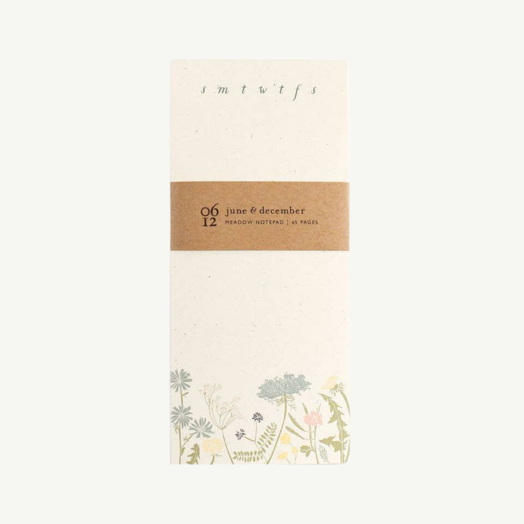 A photo of a June & December brand Daily To-Do notepad with pastel meadow botanicals along the bottom with monograms of each day of the week along the top.